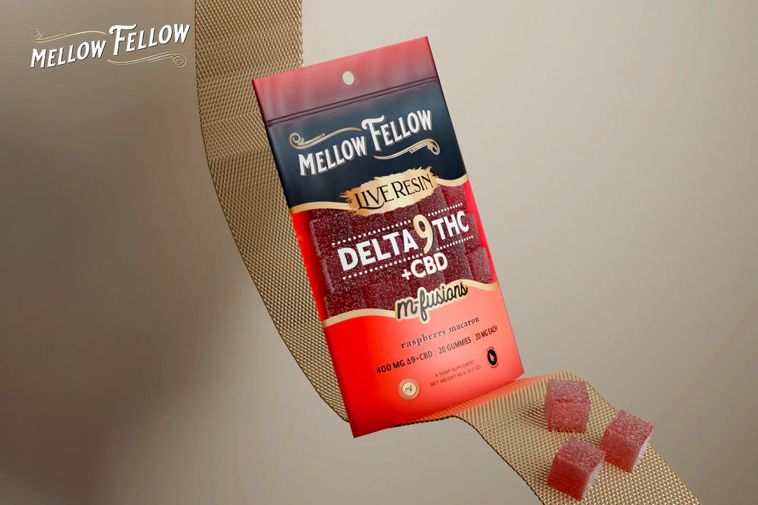 A pack of Mellow Fellow Live Resin Delta-9 THC M-Fusions in Raspberry Macaron flavor sits on a gold ribbon, with gummies scattered around