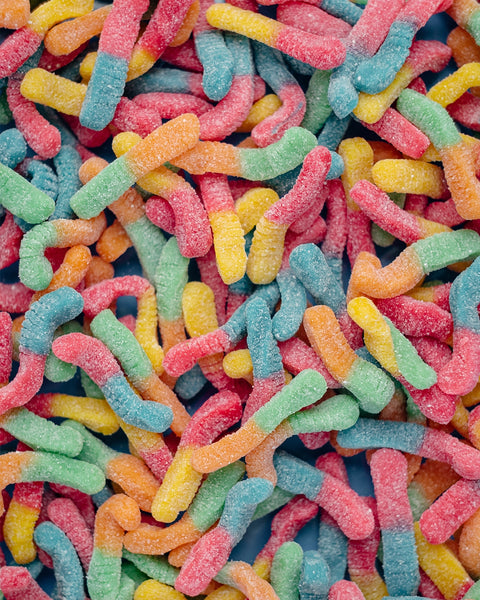 Some multicolored gummy worms are scattered