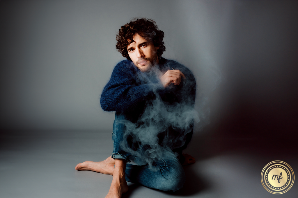 Man sitting on the floor hitting a disposable vape.