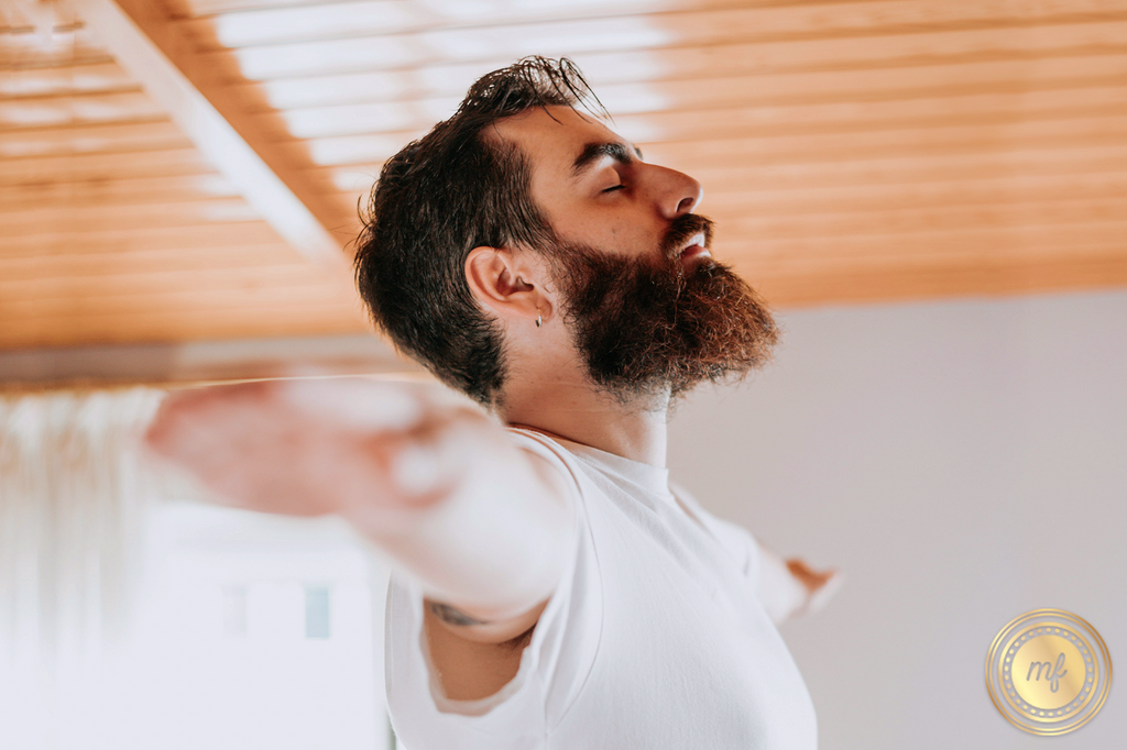 A man peacefully closing his eyes, stretching his arms out in a yoga pose