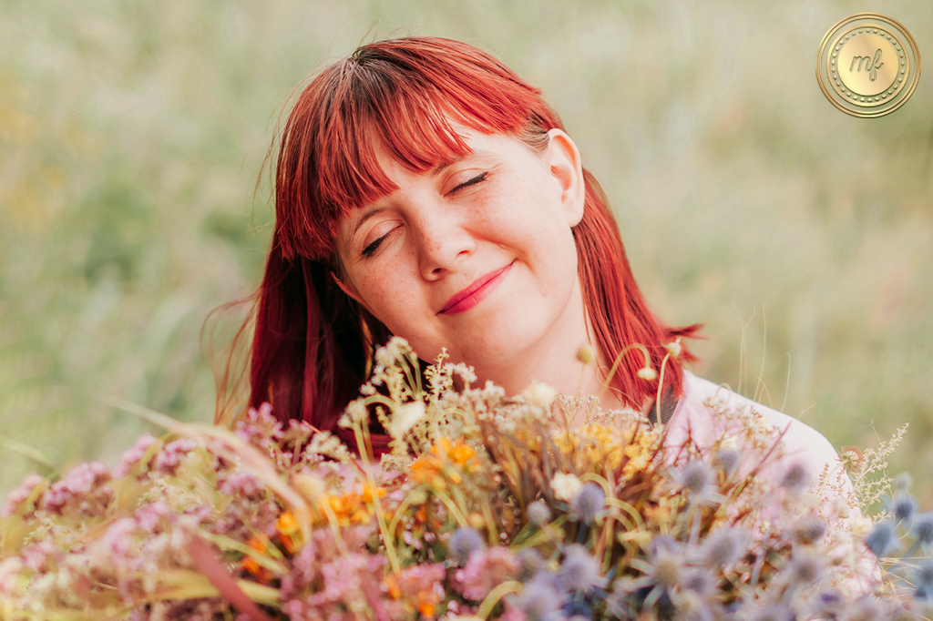 A lady stands in front of terpene flowers, eyes closed, feeling wonderful