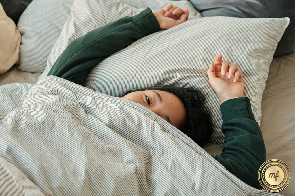 A lady lies on her bed with one eye slightly open, as if feeling sleepy