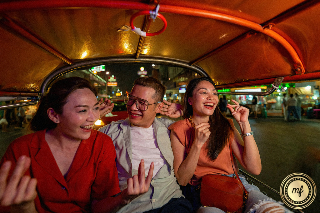 Two women and a boy ride a tuk-tuk, giggling as if under the influence of a weed strain