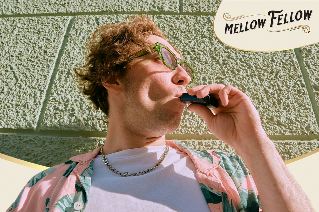 A man stands and holding a vape cartridge between his lips