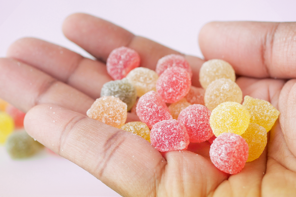 Red and yellow colorful gummies placed on the palm of a hand