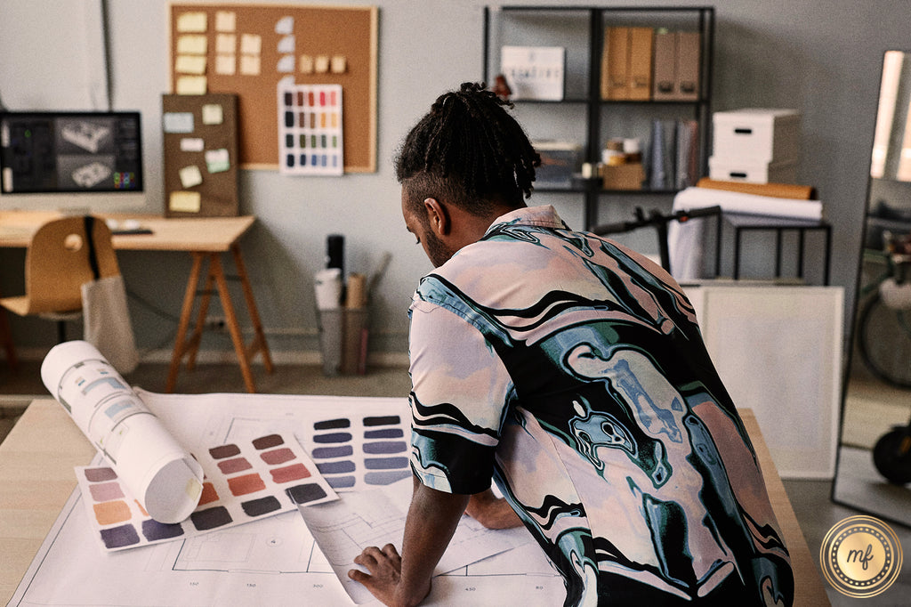 A designer studies blueprints and color swatches in a modern studio filled with creative tools and inspiration boards