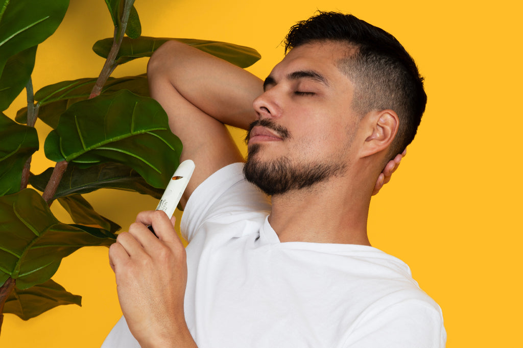 A man sits beside a tree with his eyes closed in relaxation, holding a Mellow Fellow DESTINATION series vape device