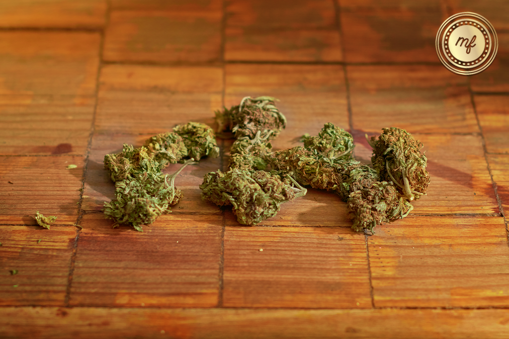 Some cannabis buds placed on a wooden surface