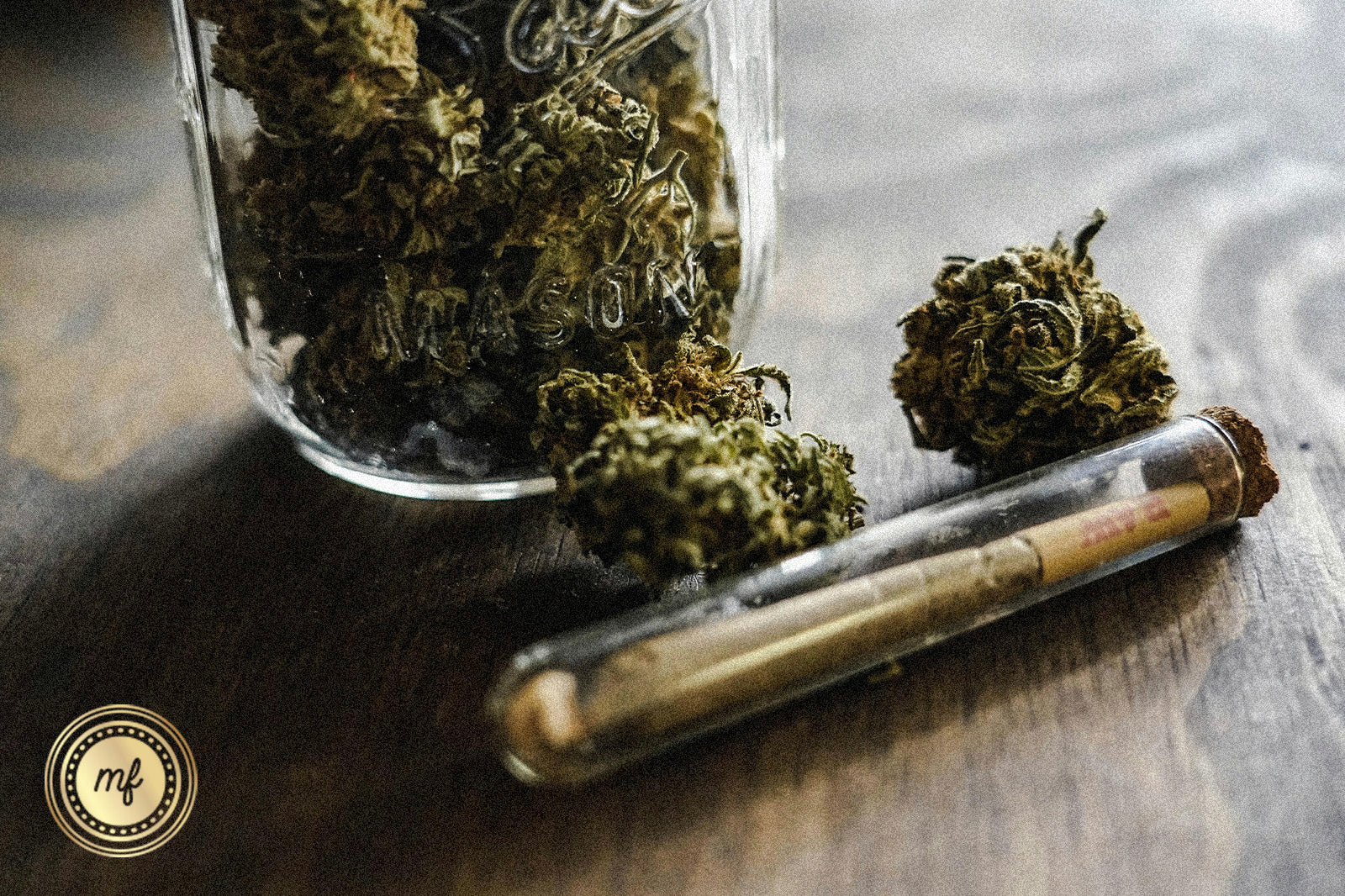 Jar with marijuana buds and a joint next to it.