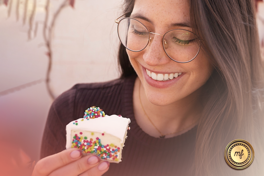 lady is holding an ice cream cake in her hand and smiling as she enjoys eating it