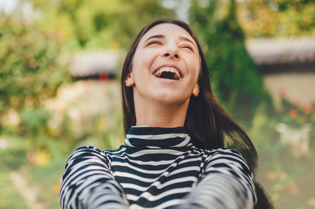 A lady is outdoors and smiling, as she is in a happy mood