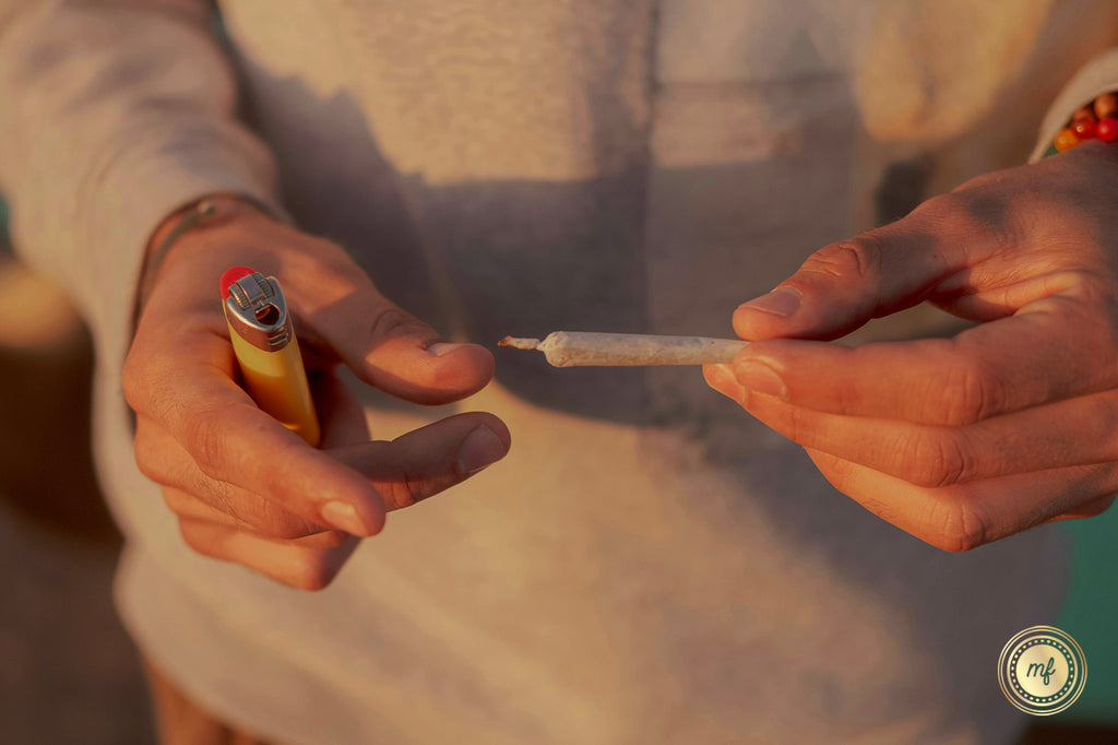 A man holding a lighter in one hand and a pre-roll in the other