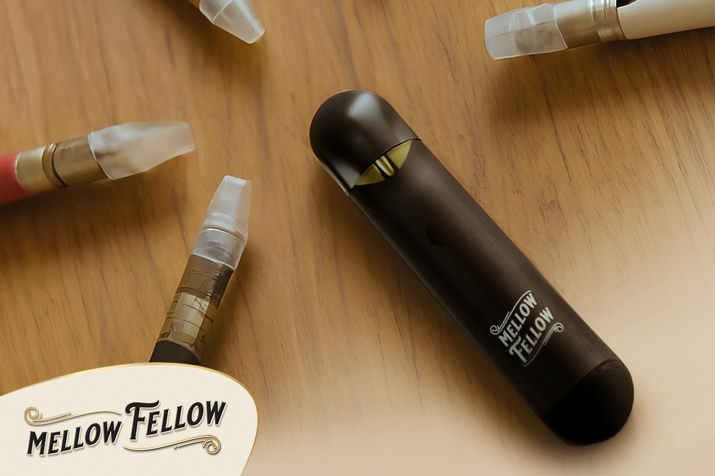 A  black Mellow Fellow vape device lies on a wooden surface & surrounded by some vape cartridges