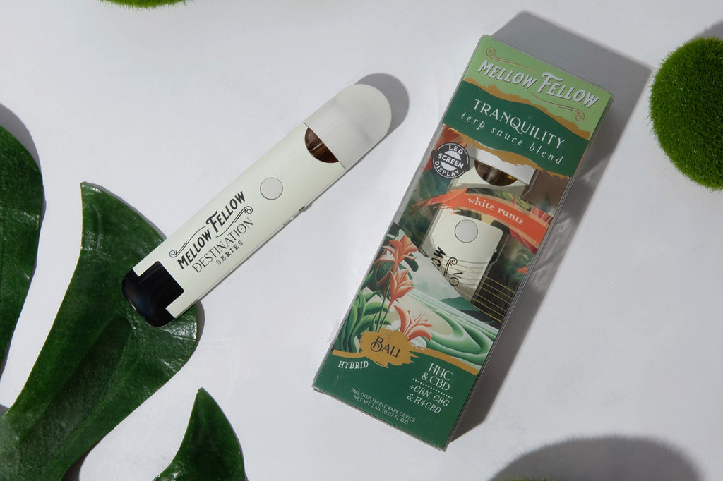A Mellow Fellow TRANQUILITY White Runtz flavored vape device with its pack placed on a white surface with some green leaves